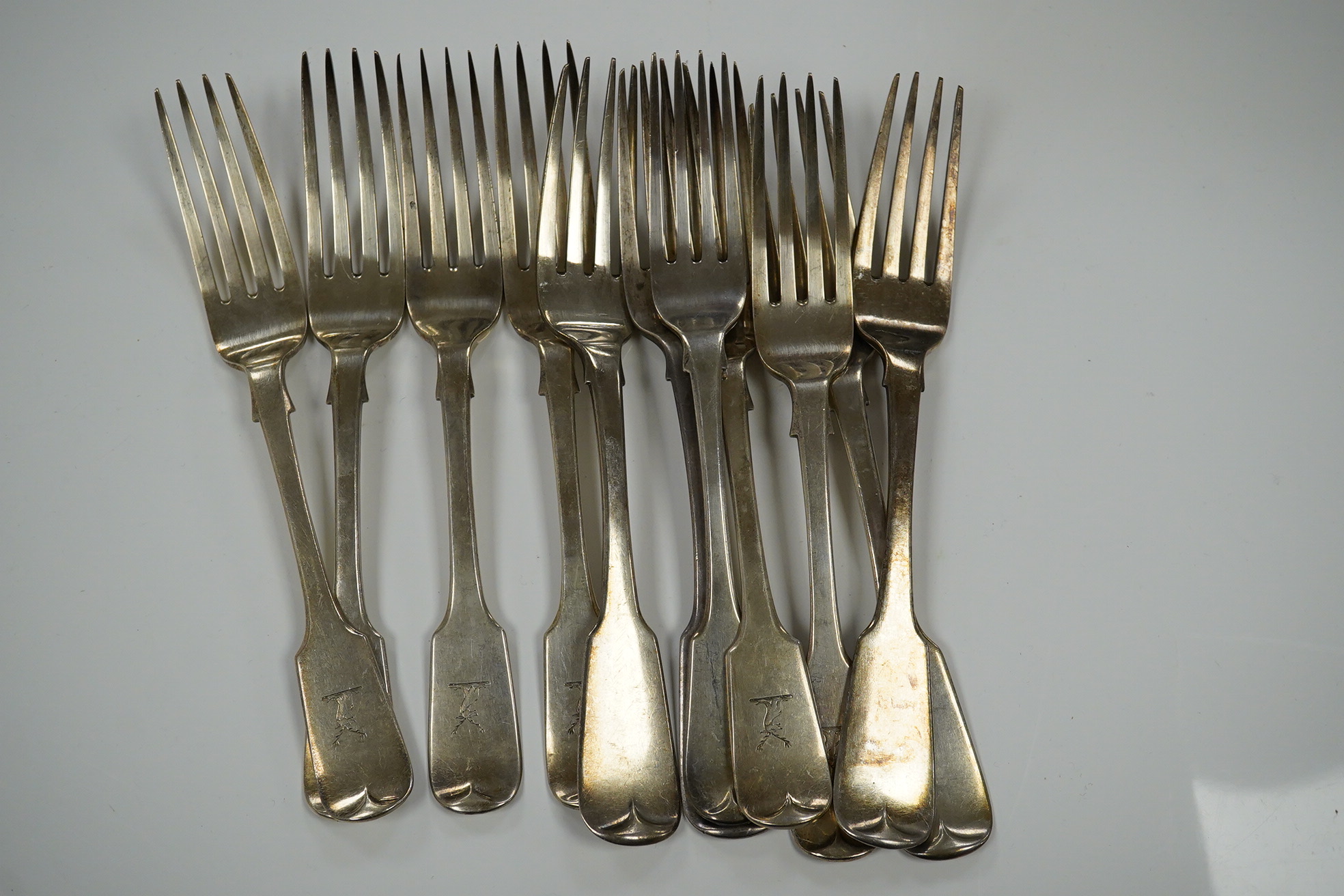 Eleven mainly 19th century silver fiddle pattern table forks, various dates and makers, 25.4oz. Condition - poor to fair